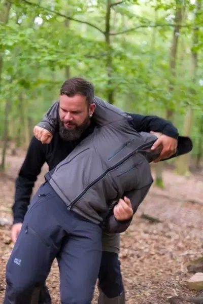 Zwei Personen üben eine Technik zur Selbstverteidigung im Wald