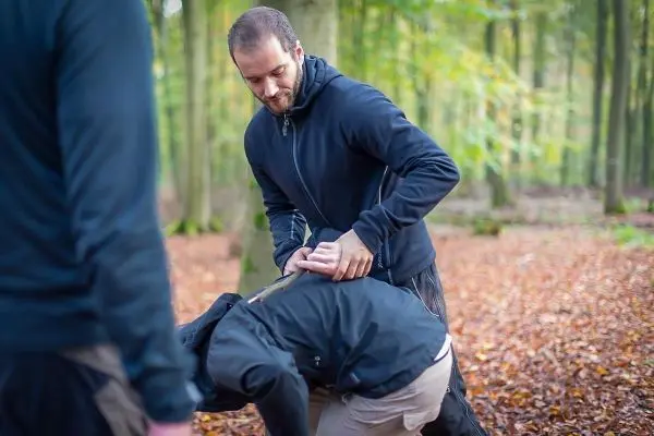 Eine Person übt eine Technik zur Kontrolle eines anderen im Wald aus
