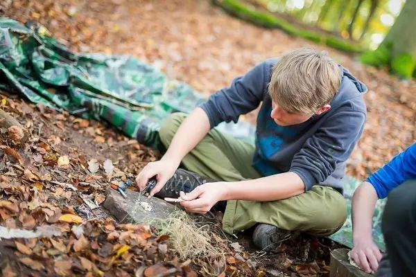 Feuerstahl erzeugt Funken auf Zunder im Laubwald