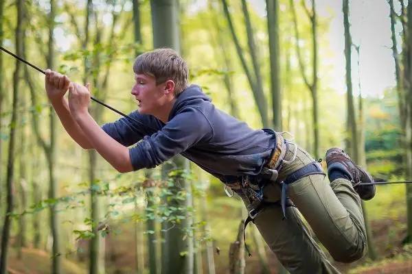 Junge überquert eine selbstgebaute Seilbrücke im Wald