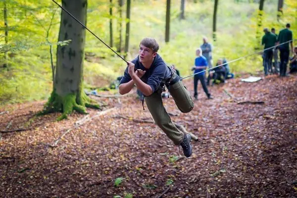 Junge überquert selbstgebaute Seilbrücke im Wald
