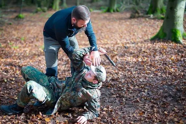 Kämpfer kontrolliert am Boden liegenden Gegner mit einem Messer in der Hand