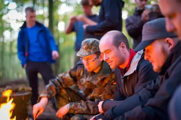 Kleine Flamme brennt vor mehreren Personen im Wald