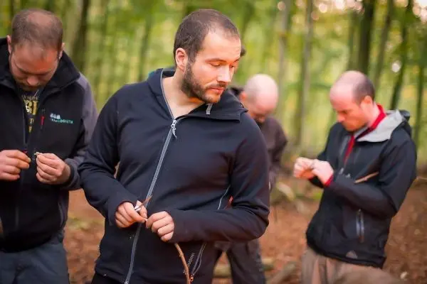 Männer bearbeiten Holzstücke mit Messern im Wald