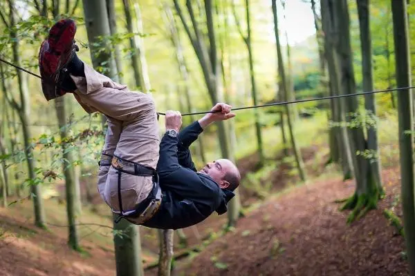 Mann überquert eine selbstgebaute Seilbrücke im Wald