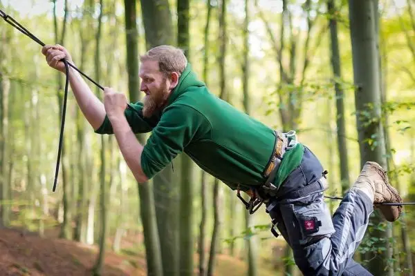 Mann überquert eine selbstgebaute Seilbrücke im Wald