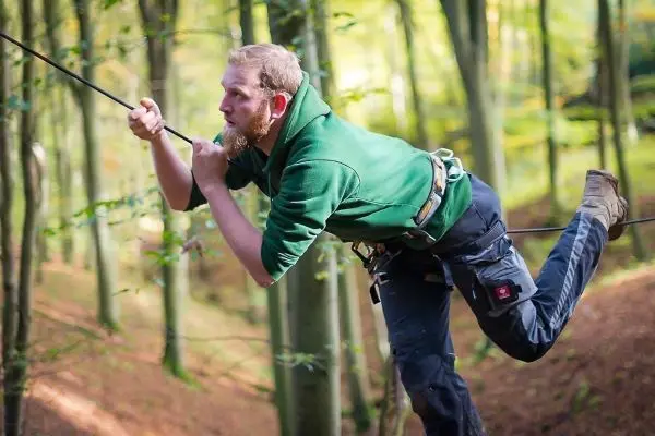Mann überquert selbstgebaute Seilbrücke im Wald