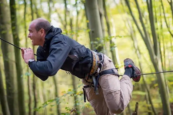 Mann überquert selbstgebaute Seilbrücke im Wald