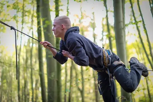 Person schwingt an einem seil zwischen baeumen