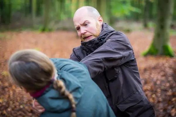Person übt eine Abwehrtechnik gegen eine andere Person im Wald