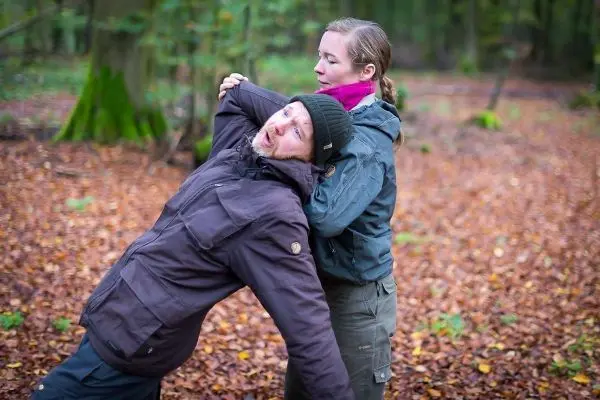 Person zeigt eine Technik zur Selbstverteidigung im Wald