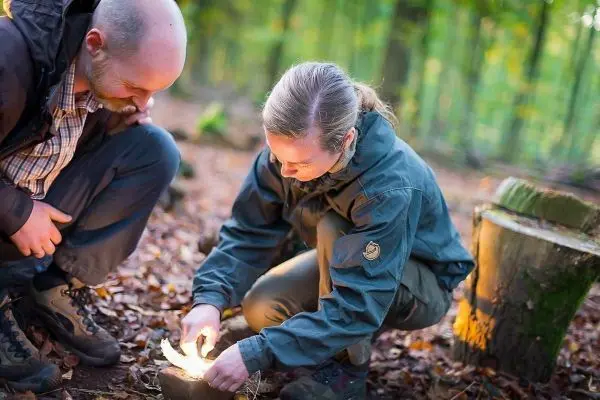 Person zündet Feuer mit Zunder im Wald beim Survival Training