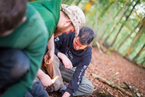 Zunder glimmt während eine Person mit Feuerstahl Funken erzeugt