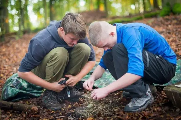 Zwei Jugendliche bereiten Zunder für ein Feuer vor