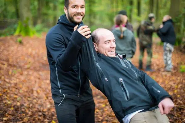 Zwei Personen stehen in einem Wald, einer hält den anderen am Arm