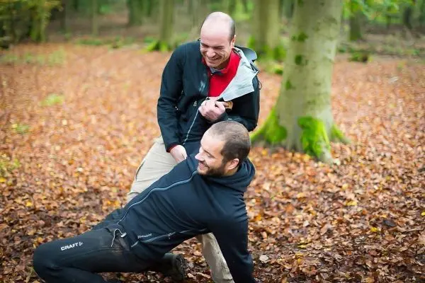 Zwei Personen üben eine Selbstverteidigungstechnik im Laubwald