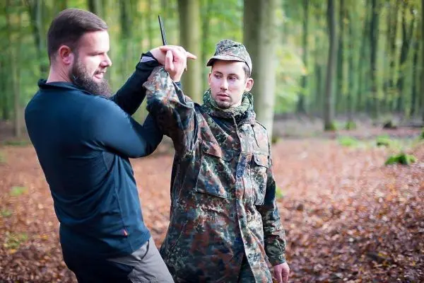 Zwei Personen üben eine Selbstverteidigungstechnik im Wald
