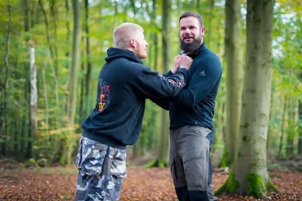 Zwei Personen üben eine Selbstverteidigungstechnik im Wald