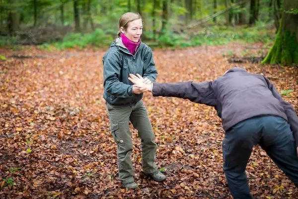 Zwei Personen üben eine Technik im Laub, eine Person greift die andere an
