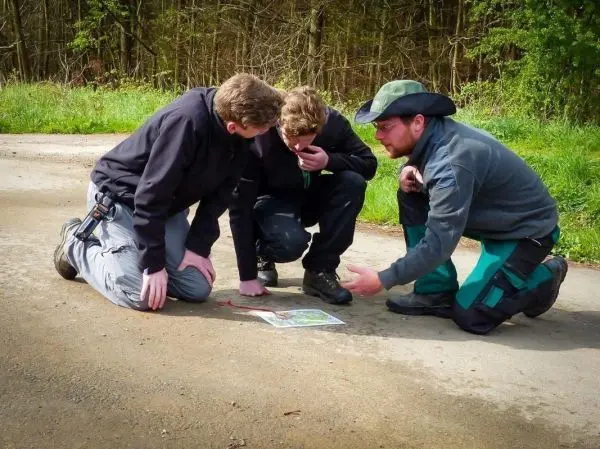 Drei Personen betrachten eine Karte auf dem Boden