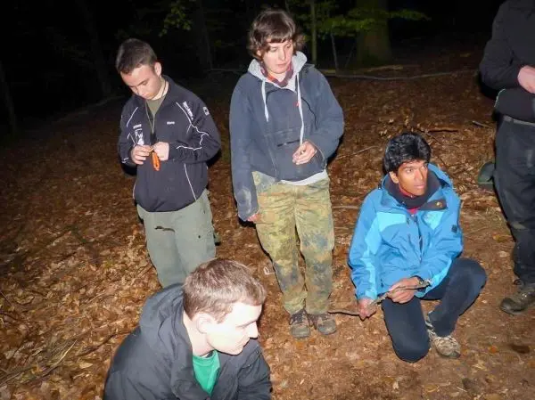 Gruppe sitzt im Laub, einige halten Werkzeuge in den Händen