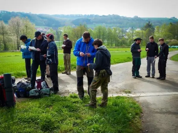 Gruppe von Personen mit Rucksäcken und Karten an einem Weg in der Natur