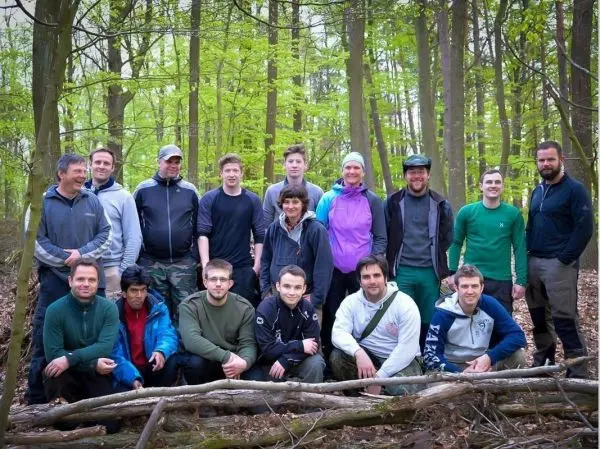 Gruppierung von Personen im Wald, umgeben von Bäumen und Laub
