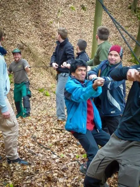 Gruppierung zieht an einem Seil in einem Laubwald