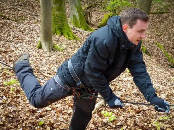 Mann überquert selbstgebaute Seilbrücke im Wald
