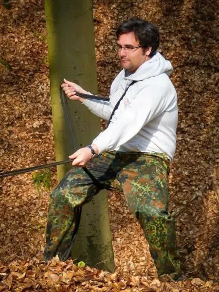 Mann zieht an einem Seil, das an einem Baum befestigt ist