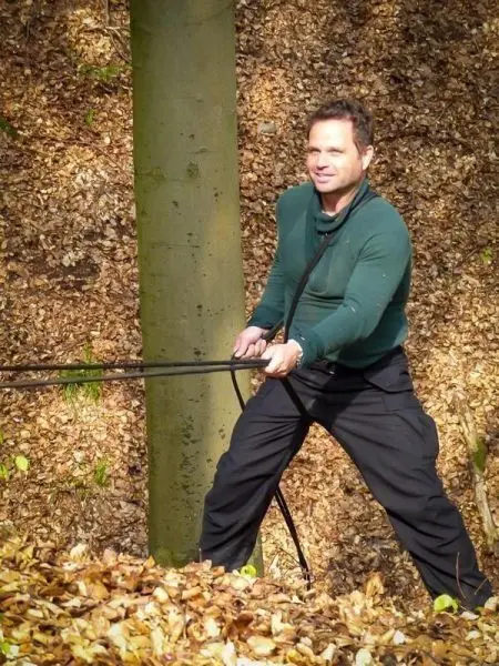 Mann zieht an einem Seil, das um einen Baumstamm gewickelt ist