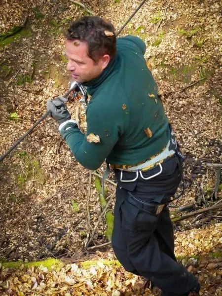 Mann zieht an einem Seil während einer Seilquerung im Wald