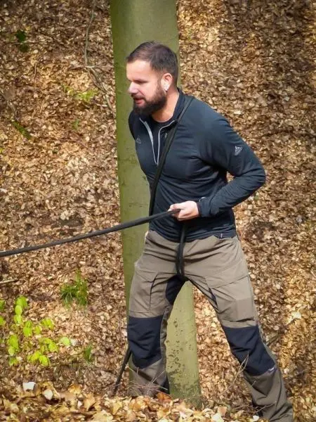 Mann zieht an einem Seil, während er an einem Baum steht