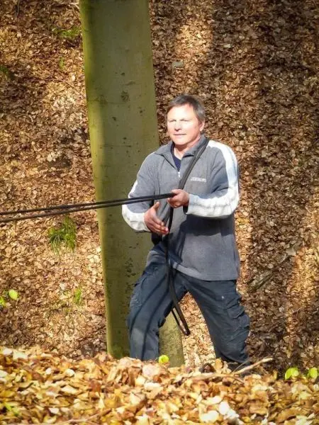 Mann zieht an einem Seil, während er auf einem Laubboden steht