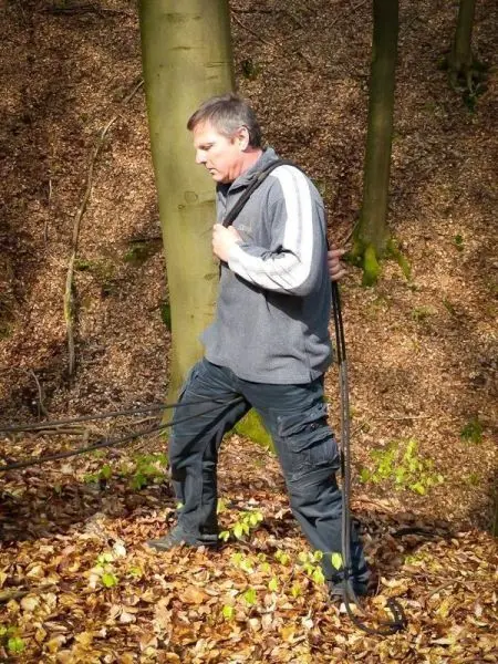 Mann zieht Seil über den Boden im Wald zwischen Bäumen