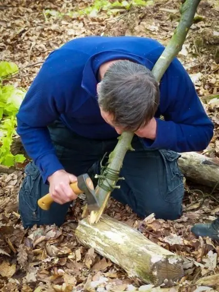 Messer schneidet Holzstück während Person sich über die Arbeit beugt
