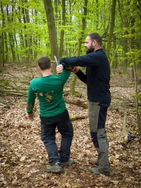 Person demonstriert eine Technik zur Selbstverteidigung im Wald