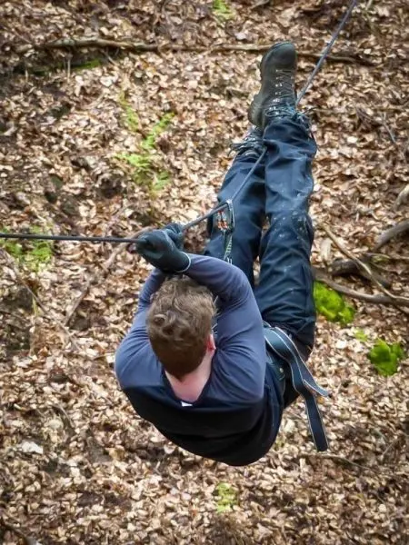 Person seilt an einem Seil durch den Wald