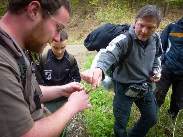 Person zeigt einer anderen Person etwas in der Hand beim Überlebenstraining