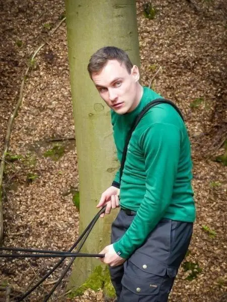 Person zieht an Seilen neben einem Baum
