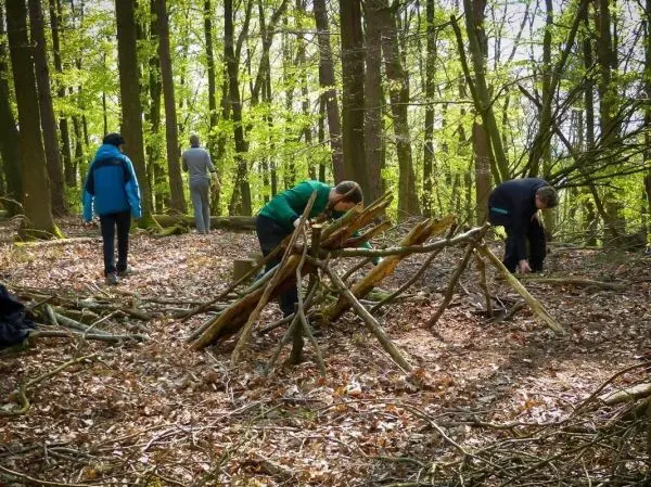 Personen bauen eine Struktur aus Ästen im Wald beim Survival Training