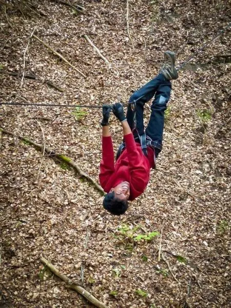 Seilquerung mit einem Seil, Person hängt kopfüber in der Luft