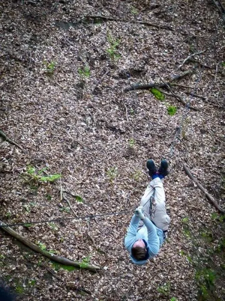 Seilquerung über Laubboden mit gesichertem Seil und abgehängter Person