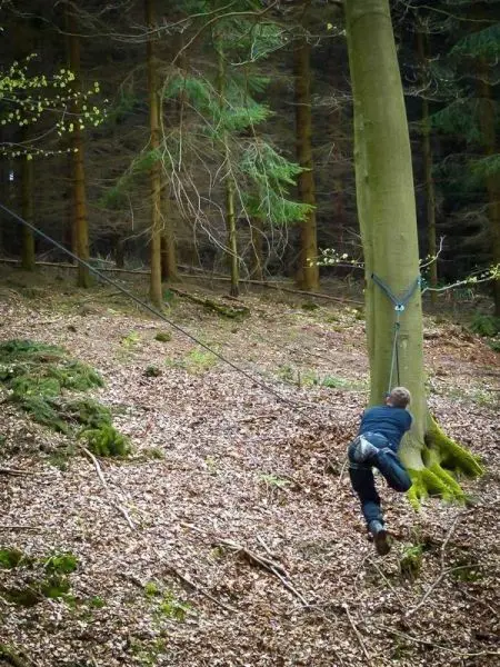 Selbstgebaute Seilquerung über den Boden, Person hält sich an einem Seil fest