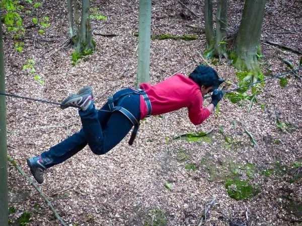 Überquert eine selbstgebaute Seilbrücke in einem Waldgebiet