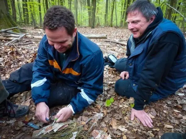 Zunder wird auf dem Boden vorbereitet, während zwei Personen daneben sitzen