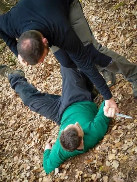 Zwei Personen im Wald, eine Person hält die andere am Arm fest