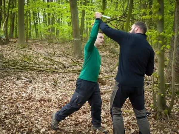 Zwei Personen üben eine Selbstverteidigungstechnik im Wald
