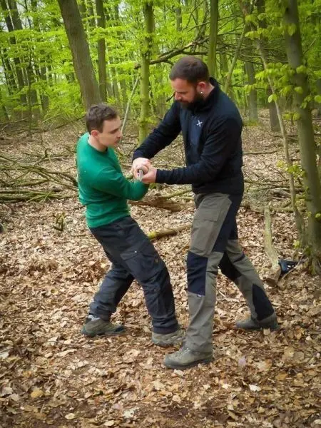 Zwei Personen üben eine Technik zur Kontrolle im Wald auf Laubboden