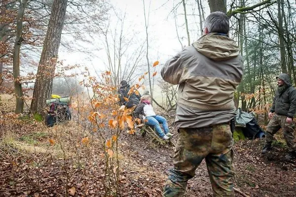 Gruppe arbeitet an improvisierter Trage im Wald, um eine Person zu transportieren